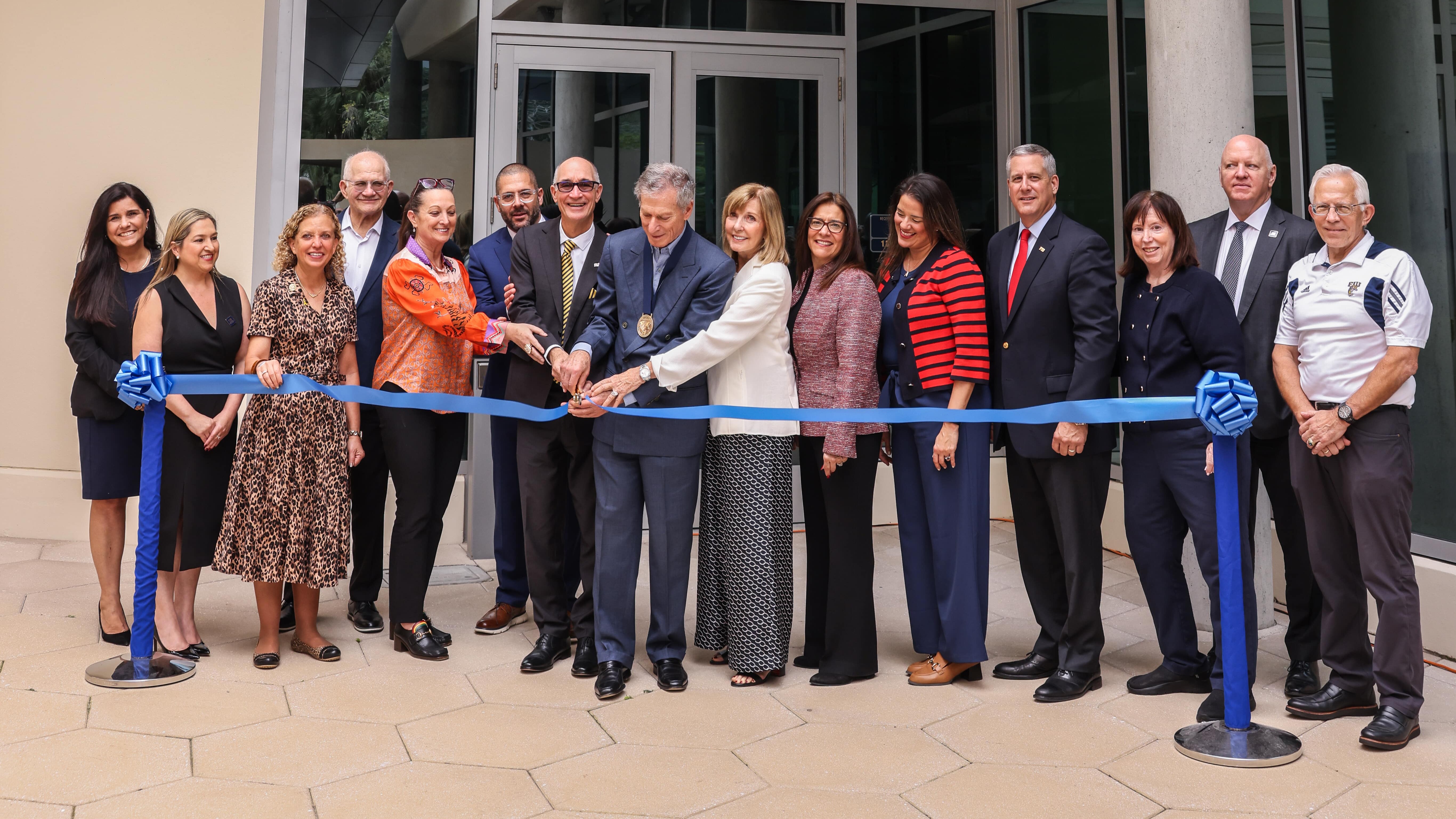 A group of FIU staff excitedly cutting the ceremonial ribbon in front of the SIPA 2 building.