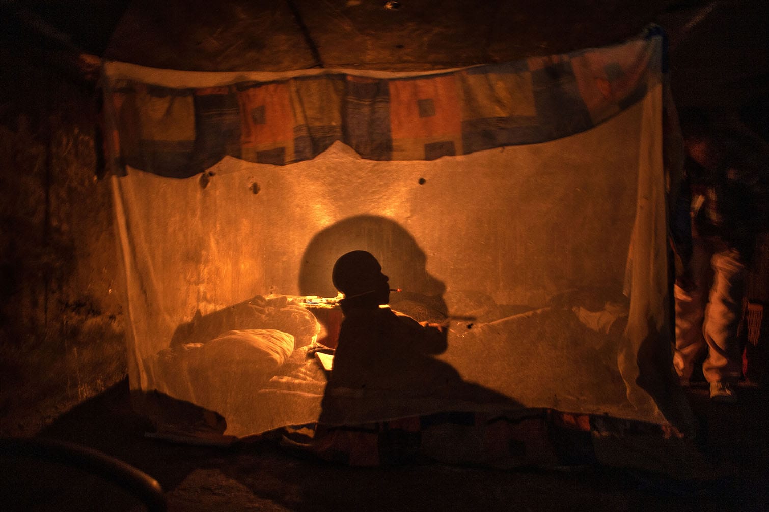 A man poses for a photograph, inside his home, in a bridge, in Johannesburg, South Africa. The opening under the bridge is no bigger than a manhole. Picture: Alon Skuy